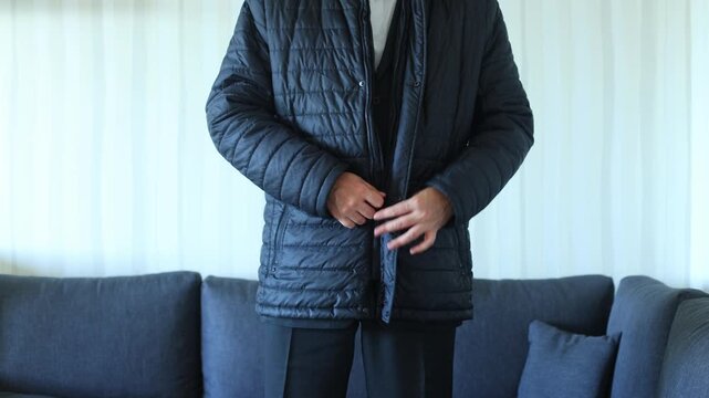 A man zips up a black quilted jacket over formal attire, capturing the transition from indoors to outdoors, readiness, and practical elegance.