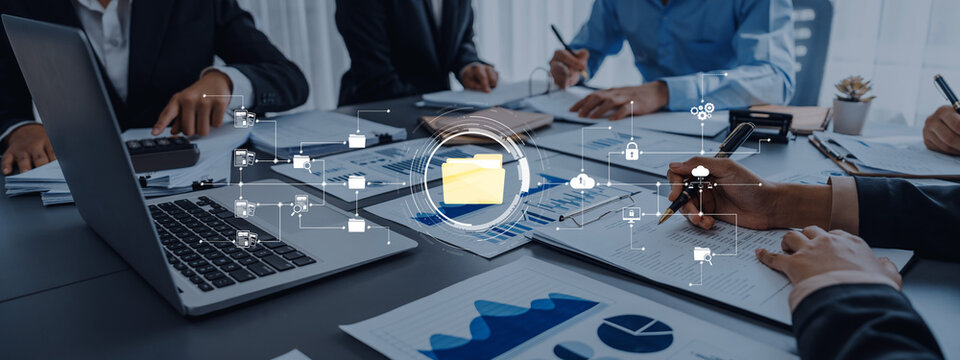 A dynamic business meeting showcasing professionals engaged in discussions, analyzing digital documents and data visualizations, promoting teamwork and strategic planning. Trope