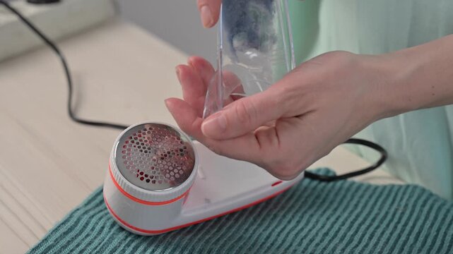 A woman revives the look of her knitted garments with a lint remover.