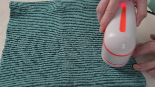 A woman revives the look of her knitted garments with a lint remover.