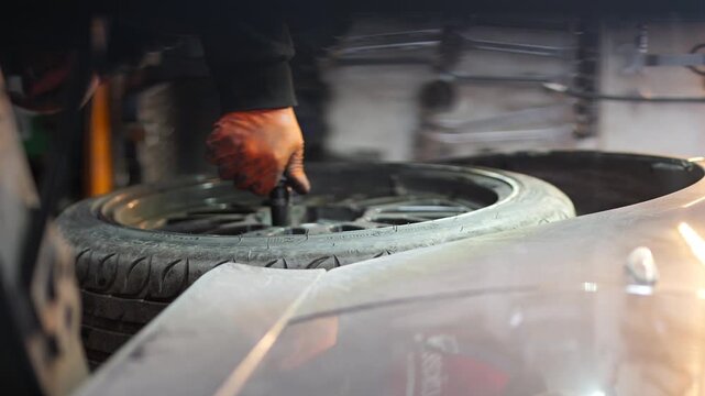 A close-up video shows a professional mechanic tightening wheel bolts with a torque wrench, ensuring precise force application for safe and secure installation of the car wheel, 2026