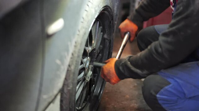 A close-up video shows a professional mechanic tightening wheel bolts with a torque wrench, ensuring precise force application for safe and secure installation of the car wheel, 2026