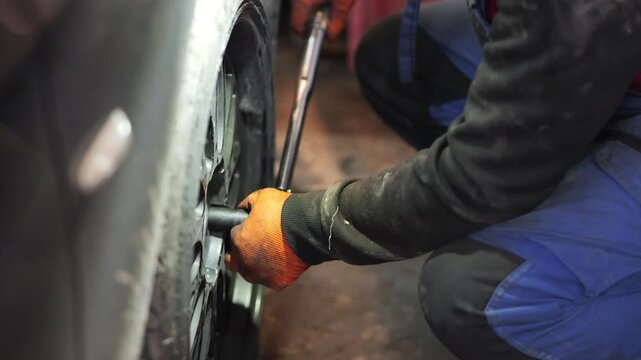A close-up video shows a professional mechanic tightening wheel bolts with a torque wrench, ensuring precise force application for safe and secure installation of the car wheel, 2026