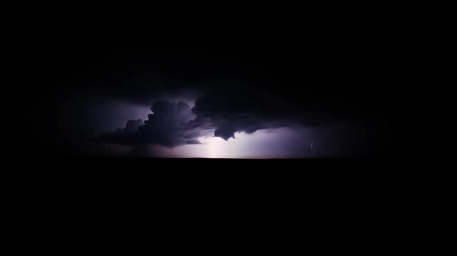 Dramatic lightning strikes illuminate dark storm clouds over flat landscape at night