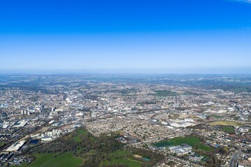 Obraz premium Wide aerial view of the city of Bradford West Yorkshire UK showing urban housing industrial estates and green spaces across rolling terrain captured from a high vantage point in clear daylight