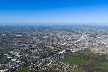 Fototapeta premium Aerial view of suburban housing in the city of Bradford West Yorkshire UK with nearby cemetery main road and green parkland captured from above in daylight conditions in early spring