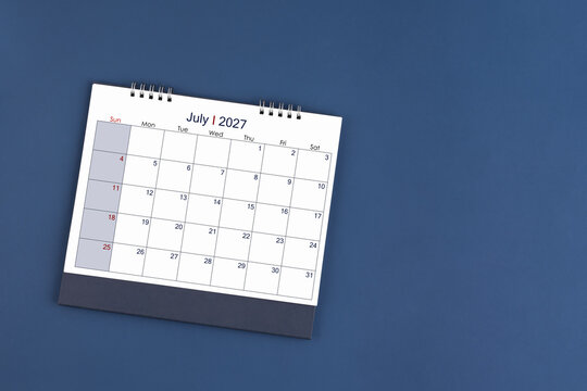 July  2027 Monthly desk calendar on blue color background, Position with copy space. Flat Lay.