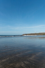 Waves from the Pacific ocean crashing onto a sandy tropical beach with a distant green coastline under a clear blue sky, showing serene natural beauty - stock photo © Amaiquez
