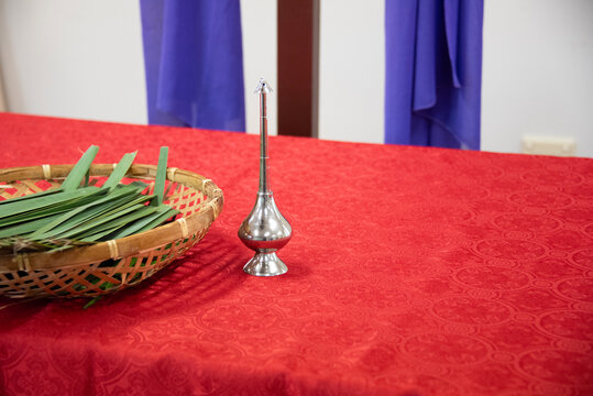 Palm fronds in a basket with a holy water sprinkler on an altar table, preparing for a christian religious service