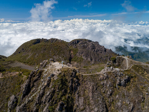 Volcan Baru summit cross rising above a vast expanse of clouds, showcasing the stunning aerial landscape of Chiriqui, Panama, with distant mountains and clear blue sky - stock photo