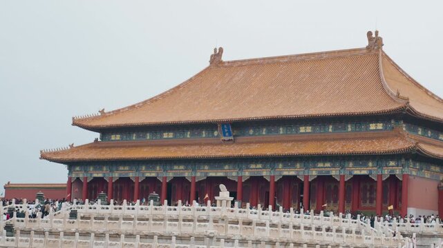 Caucasian observer framed forbidden palace roof ornate glazed tiles and gilded eaves, close architectural study, blurred foreground figure, calm overcast sky, symmetry and craftsmanship on display