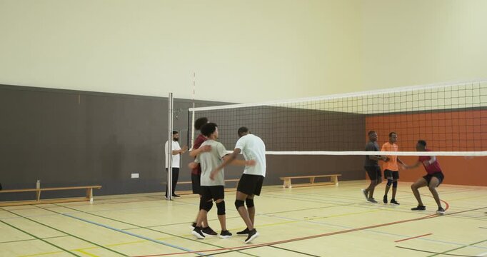 Diverse male teams wearing pads initiating play with serve at net, competing for point, celebrating