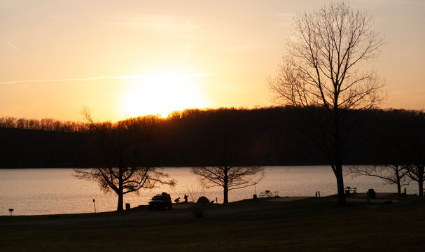 Sunset at the lake, people fishing, picnic tables, silhouette