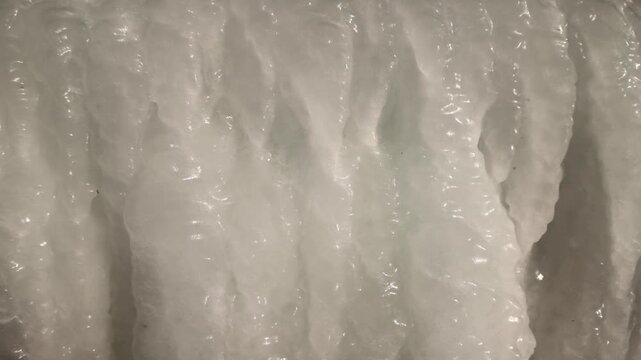 Close-up panorama of icicles hanging from roof. Winter scene with continuous hanging ice. Natural pattern of icing on sunny winter day.