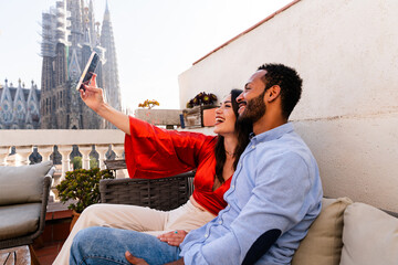 Obraz premium Multiracial beautiful happy couple of lovers dating in Barcelona on a rooftop with amazing city view
