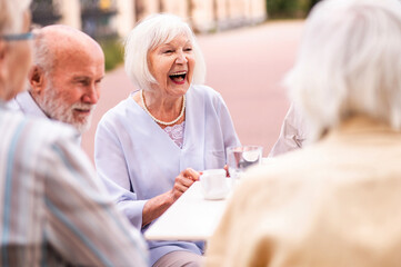 Group of happy senior friends meeting outdoors at the bar cafè and having a conversation, concepts about elderly, lifestyle and quality of life