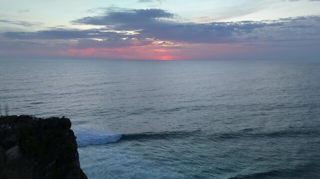 Plans drone 4K d'Uluwatu, Bali, lors de la blue hour : falaises majestueuses, oc&eacute;an Indien, lumi&egrave;res bleut&eacute;es et ciel cr&eacute;pusculaire. Id&eacute;al pour projets voyage, nature, architecture et Asie tropicale