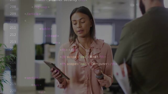 Talking woman in pink blouse holding tablet, gesturing in open office, papers right, code overlay