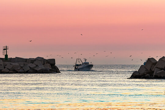 Fishing boat leaving Sciacca harbor at sunset