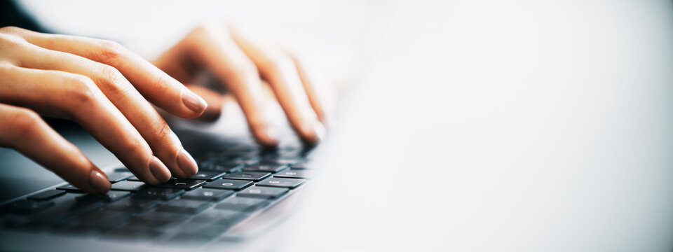 Close-up of person's hands typing on a laptop keyboard with bright empty background creating clean modern copy space for design and communication.