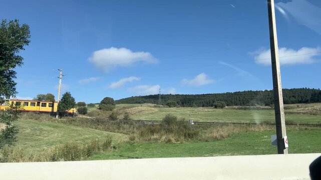 Famous yellow tourist train running through the green landscape of Font Romeu in the Pyrenees