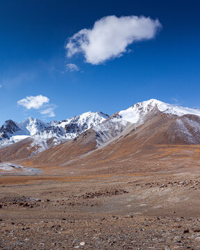 Snow-capped mountain peaks against vivid blue sky, rugged Pamir Plateau landscape along Karakoram Highway in Xinjiang, China