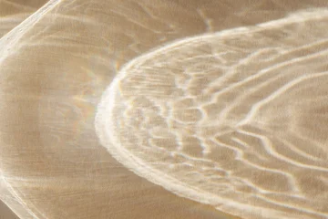 Shiny golden abstract shadows background from sunlight and glare. Modern caustic background from reflection effects for product presentation and design card. © juliasudnitskaya