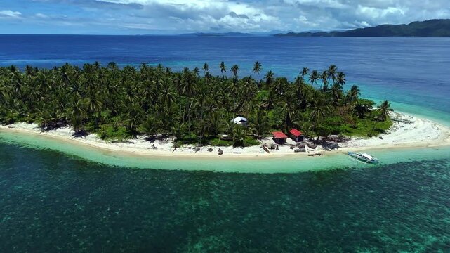 Aerial point of view of Basul Island in Surigao, Philippines with white sand beaches and coral shoals panning left to right.