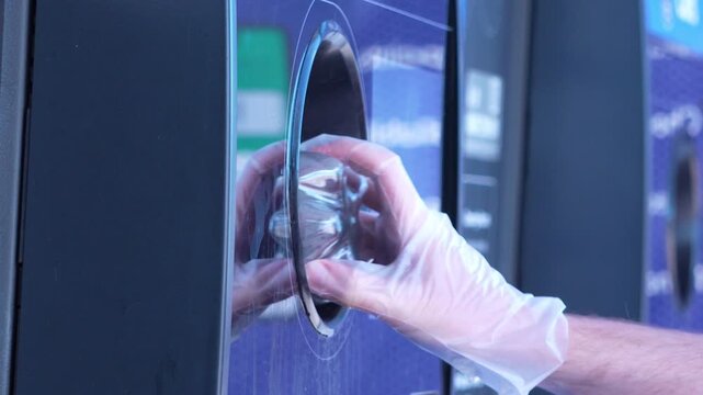 Static side view close-up of a person placing bottles and cans into a recycling refund machine. Clean, practical shot highlighting sustainability, recycling behaviour, and container deposit schemes. 