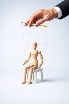 Wooden puppet manipulated by hand micromanagement control figure on stool emotional power dynamic