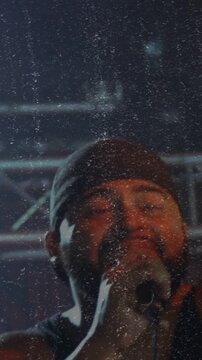 Vertical video: Cam revealing singer singing into mic, performing music onstage with grain overlay