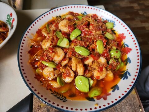 Spicy shrimp cooked with petai beans and chili sambal, served on a plate. Traditional Indonesian seafood dish, rich in flavor and perfect for Asian cuisine and food concepts.