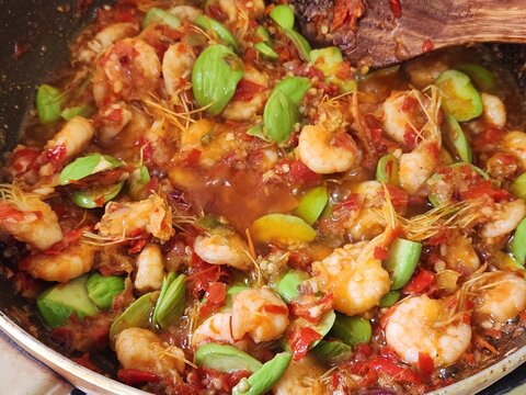 Spicy shrimp cooked with petai beans and chili sambal, served on a plate. Traditional Indonesian seafood dish, rich in flavor and perfect for Asian cuisine and food concepts.