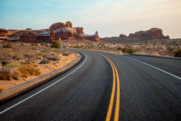 Expansive Twolane Utah Highway Leading Towards Distant Desert Horizon Under Bright Clear Sky © Val MAK