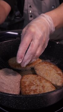 The cook cooks delicious minced meat patties in a frying pan