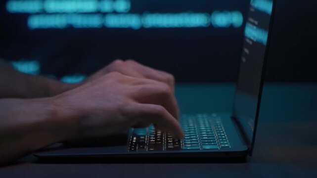 Close up of coder or data scientist hands typing on laptop keyboard with glowing programming blue script in background. Software development or cybersecurity concept. 
