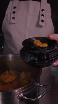Potato and meat goulash. The cook puts delicious goulash in ceramic dishes