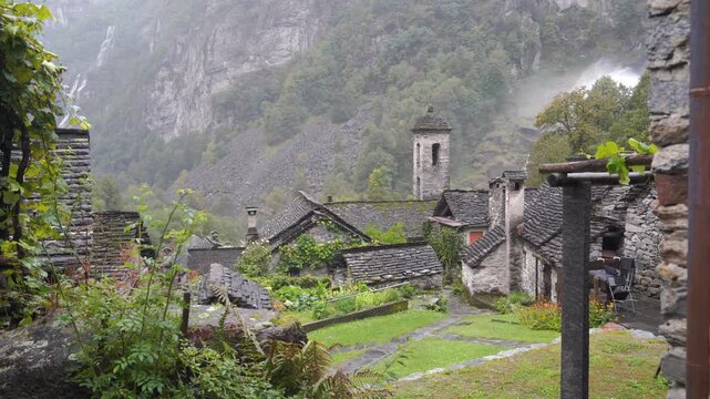 Traditional stone houses stand in the misty mountain village of Foroglio in Val Bavona, ideal for travel and hiking themes 