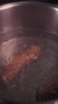 The process of cooking boiled sausages. Vertical video for a culinary blog