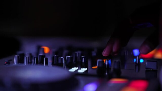 Close-up of hands controlling DJ mixer faders during a vibrant club party celebration