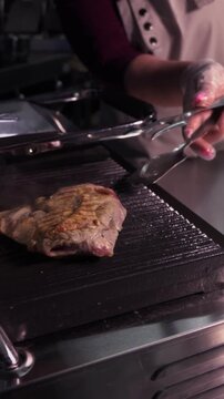 Cooking a steak. A professional chef prepares delicious meat on a hot grill.