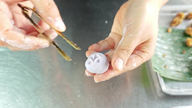 Making Chor Muang, a traditional Royal Thai appetizer, using brass tweezers to meticulously shape dough into flower petals.