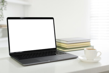 Fototapeta premium Stylish workplace with laptop, notepads and cup of coffee on white desk indoors, closeup