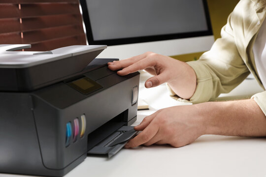 Man working with printer at white desk indoors, closeup