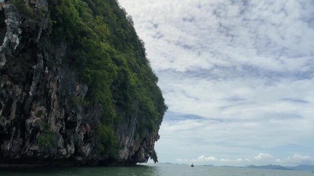 Dramatic limestone karst cliffs and lush green jungle along the sea in Phuket Thailand, tropical coastal scenery.
