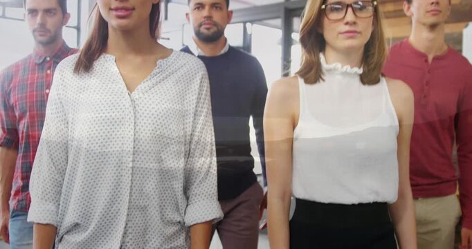 Composite video of a beach against team of diverse colleagues walking together at office