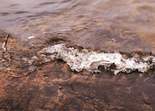 The sea wave reaches the rock. Fresh sea water. Nature photography. Closeup view of waves and their movement. Espoo, Finland.