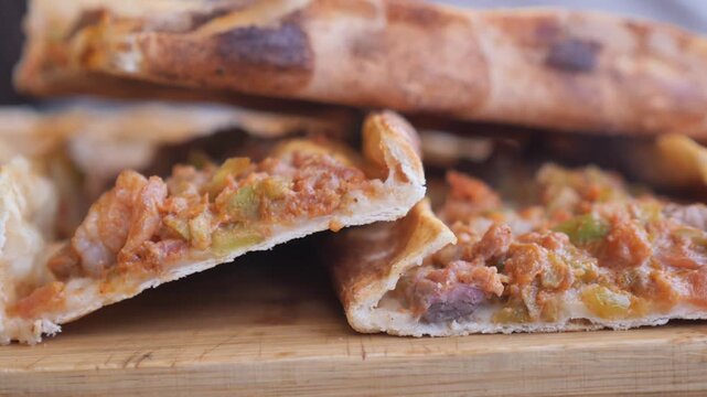Fresh turkish pide slices steaming on wooden board close up view of traditional baked food.