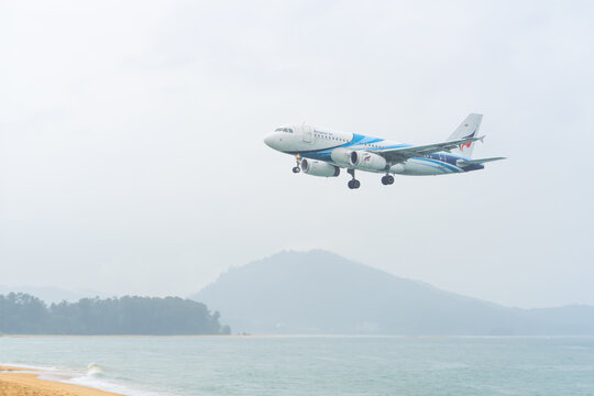 Mai Khao Phuket Thailand 2025 11 25: Airbus A319-132 from Bangkok Airways approaches landing over a beach in Thailand. The aircraft has the registration number HS-PPA and flies close to the water.