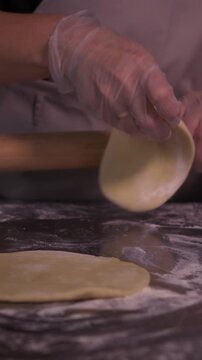 Kneading the pie dough. A woman rolls out the dough in the kitchen.
